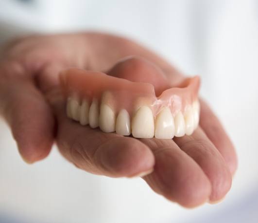 Hand holding a full upper denture